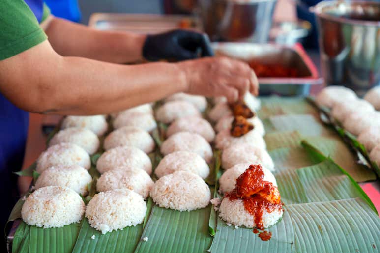 Street vendor preparing fresh Nasi Lemak on banana leaves