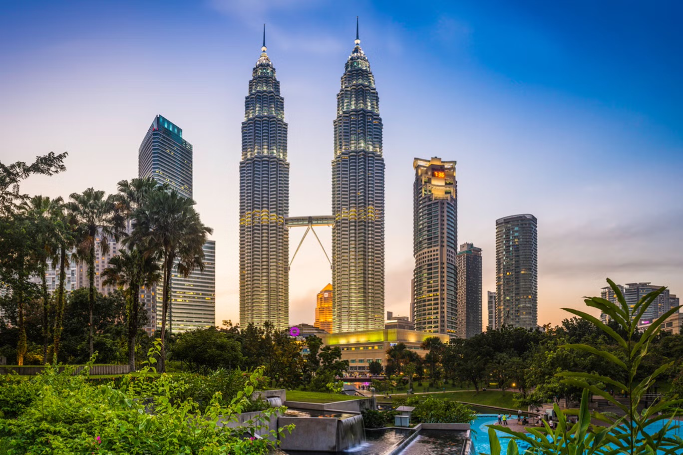 Petronas Twin Towers rising above KLCC Park at dusk